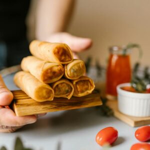 Close-up of crispy spring rolls served with dipping sauce and garnishes.